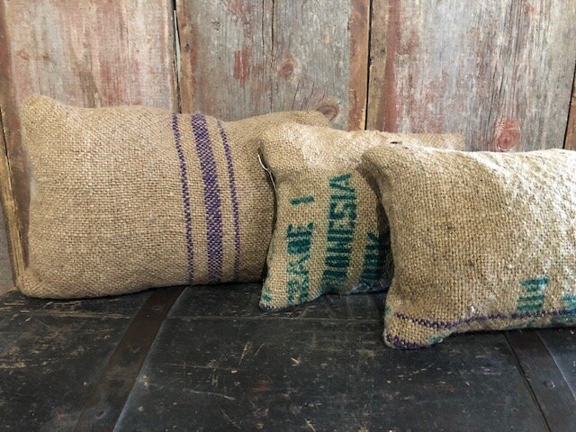 Coffee+Bean+gunny+sack+pillows Vintage burlap sacks arranged on a rustic wooden surface, showcasing different sizes and colors of the sacks, ideal for home decor or farmhouse styling.